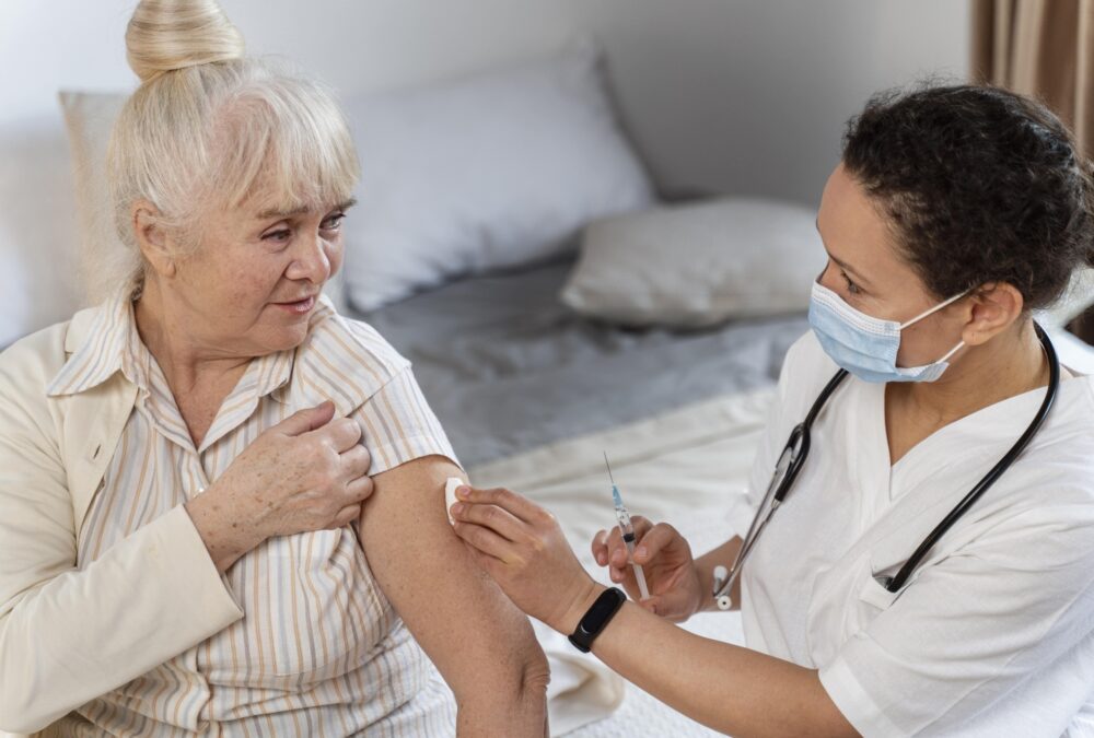 Aplicação de injeção em casa sendo realizada por profissional de saúde em paciente idosa com segurança
